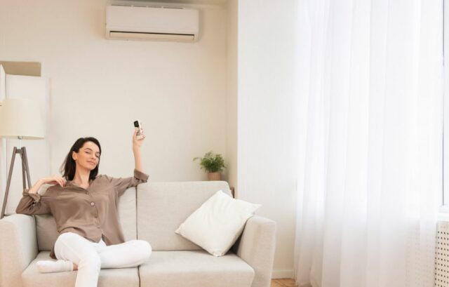 Happy woman turning on air conditioning with a remote.