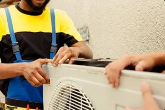 HVAC technician repairing an outdoor air conditioning unit, focusing on maintenance and repair services in Red Deer.